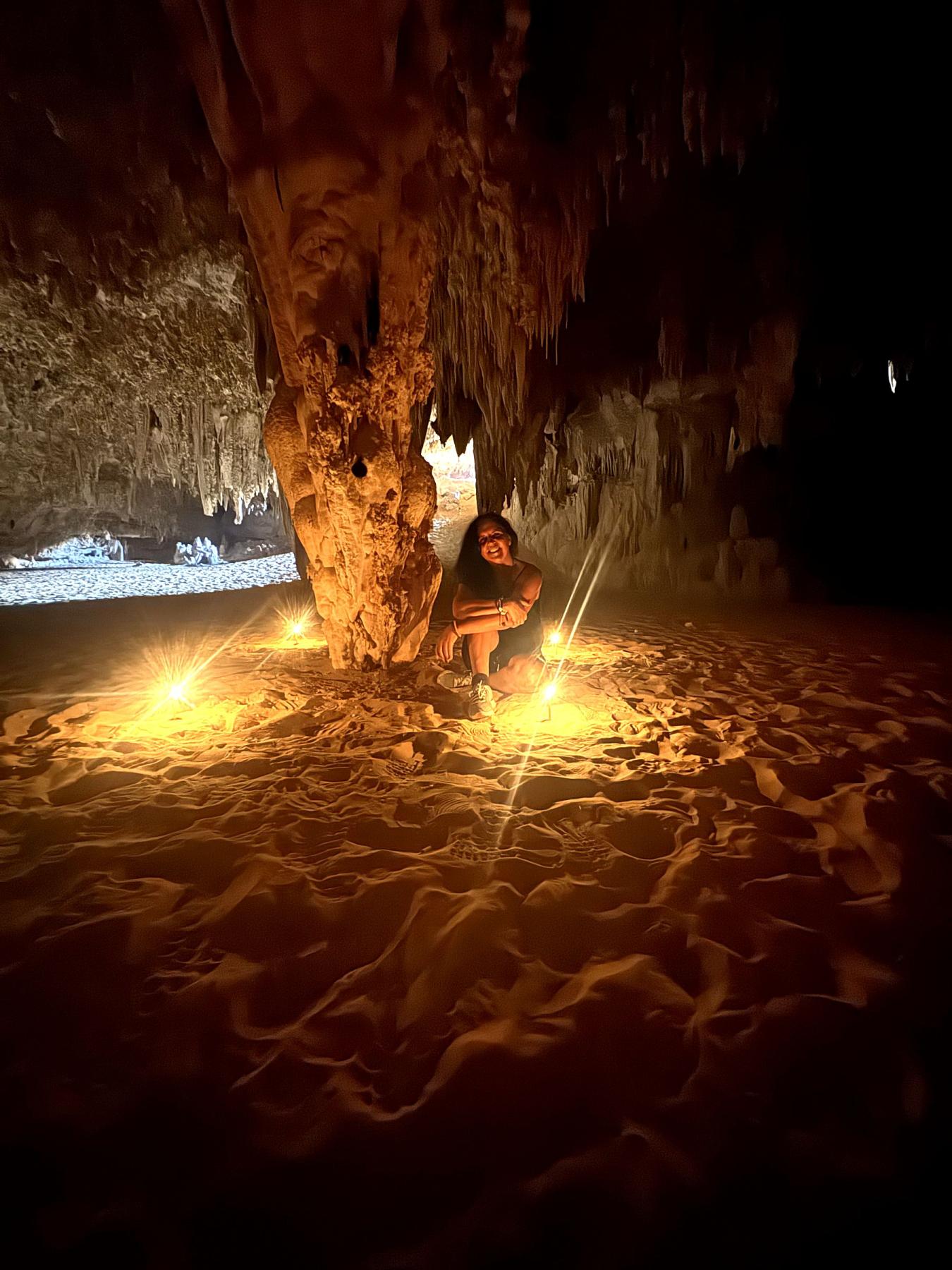 Woman meditating by candlelight inside a desert crystal cave