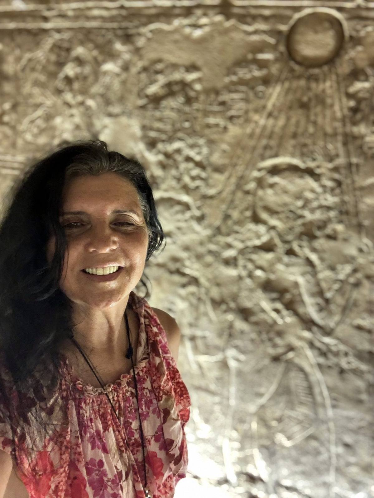 Kristina Mills beside an Aten sun disc relief at Amarna