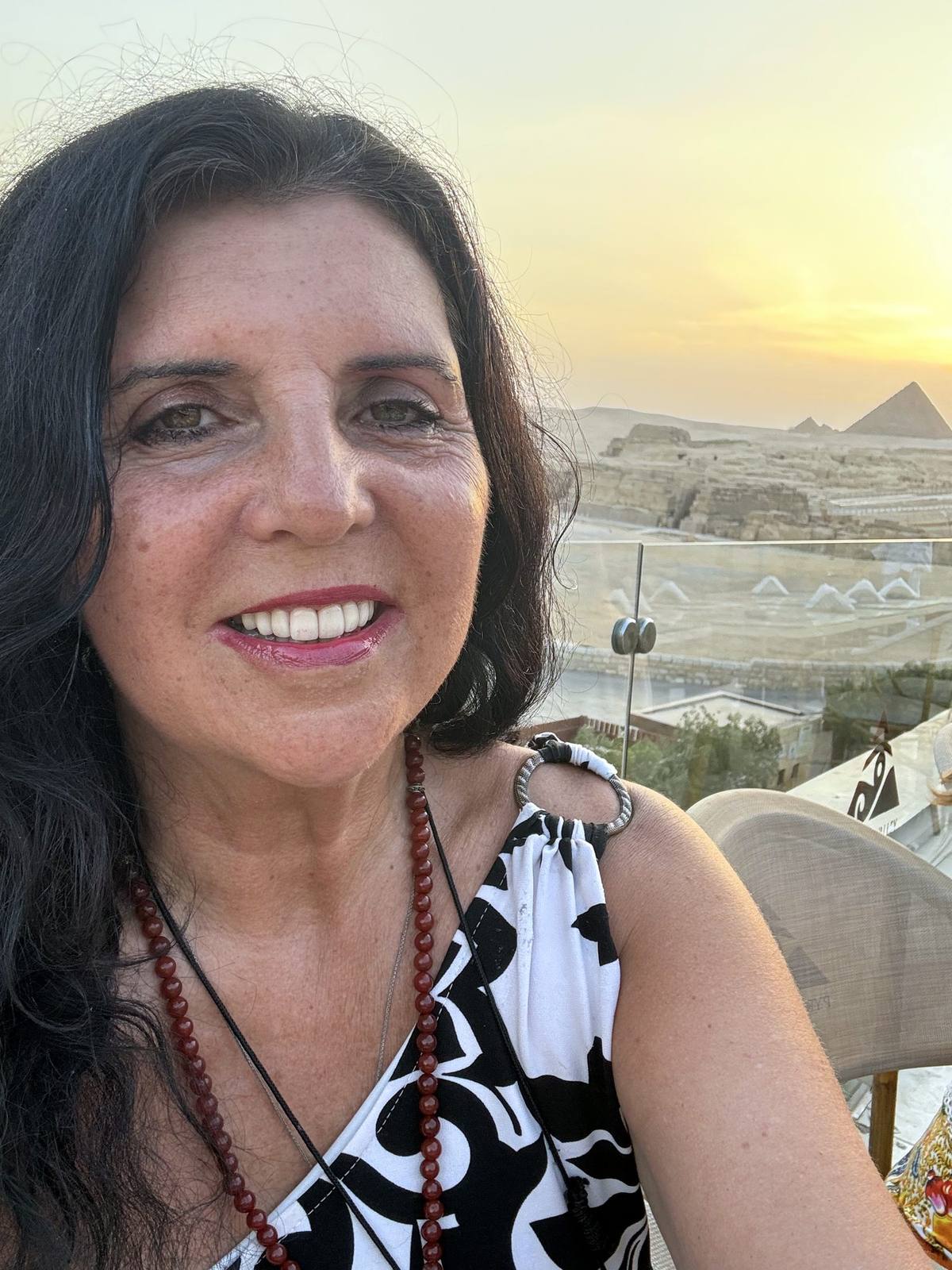 Kristina Mills smiling at sunset with the pyramids of Giza behind her
