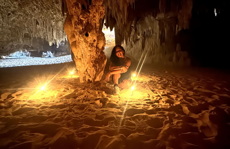 Woman meditating by candlelight inside a desert crystal cave